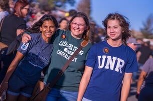 Three college students smile for a photo wearing University of Nevada Reno shirts
