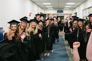 Bethel University graduates pose in their caps and gowns before entering the auditorium for commencement