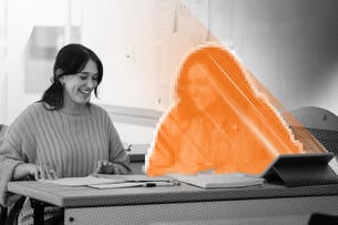 A student is tutored by an AI avatar being projected from a tablet on the desk.