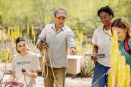 Four people, three women and a man, holding survey tools and dressed to be outdoors.
