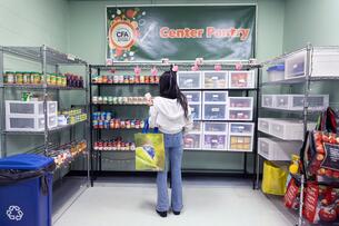 A student with a shopping basket looking at items at a food pantry on a college campus.