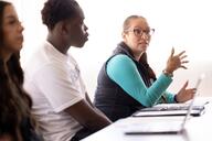 Hispanic female adult student speaking during a class in a sunny classroom on a college campus.