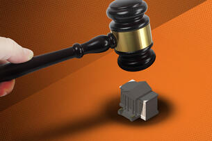 A gavel hovers over a school building. 