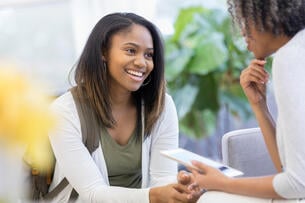 Female counselor holds digital tablet while helping a female student.