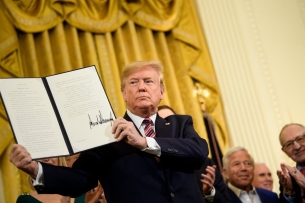 A picture of Trump holding open an executive order