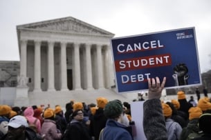 A demonstration in front of the Supreme Court; a demonstrator is holding up a sign that says "Cancel Student Debt"