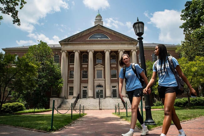 Two women walk in front of a building on UNC Chapel Hill's campus.