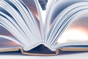 A close-up of an open book, with the pages fanning out from the spine in an aesthetically pleasing way.