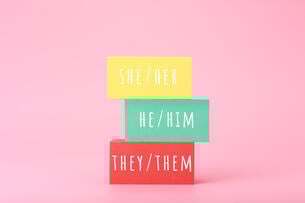 A photo illustration of three stacked blocks. The top says "she/her," the middle says "he/him" and the bottom says "they/them."