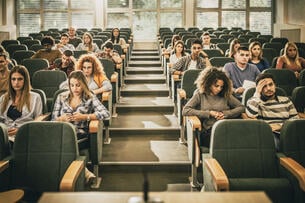 Large group of college students feeling bored while attending a class in amphitheater.