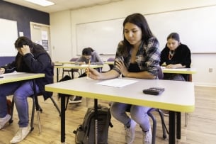 A Native American student sits at a desk with a paper in front of her.