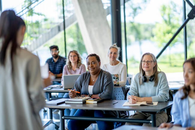A group of older students sits in a classroom. 