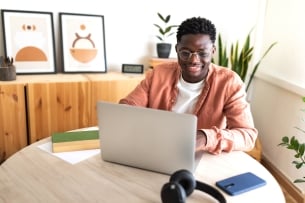 Black male university student studying at home using laptop