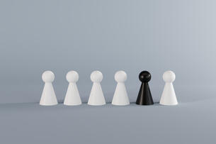A row of six pawns (chess pieces) against a gray background. Five of the pawns are white and one pawn, placed second to the right, is black.