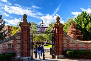 An open gate to Harvard University's campus with three students walking through it.