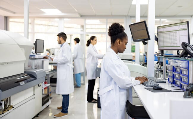 A group of four scientists of different races and genders work in a research laboratory.