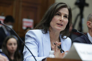 Clare Shipman, a light-skinned woman with brown hair, speaks to Congress in a blue blazer