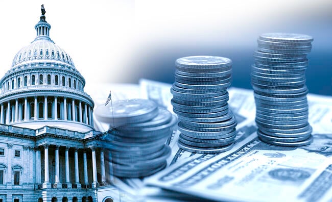 A blue-scale image of the U.S. Capitol building with stacks of U.S. currency—both dollars and coins—stacked in the foreground of the picture.