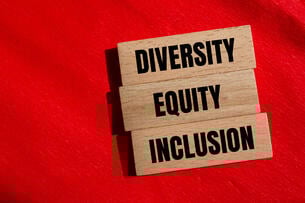 Three wooden blocks with the words "Diversity," "Equity" and "Inclusion" against a red background.