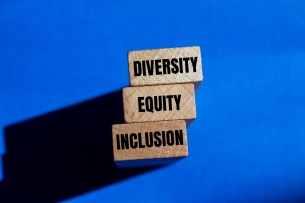 Three wooden blocks that say "Diversity," Equity" and "Inclusion" against a royal blue background.