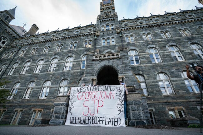 Students with sign outside building 