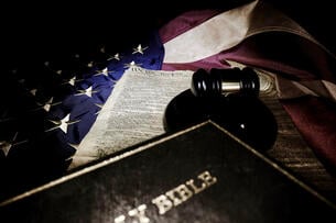 A Bible, judge's gavel and copy of the U.S. Constitution lie atop an American flag.