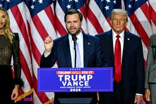 Vice President–elect JD Vance speaks during an election night event; he stands behind a podium while President-elect Donald Trump stands beside him.