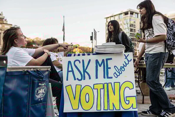 University of Pittsburgh students stand near a sign that says "Ask Me About Voting."