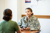 A young female soldier in a camouflage uniform listens attentively during a counseling session.
