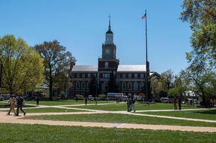 Students walk on Howard University's grassy quad with the campus library in the background.