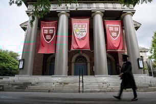A photo of the Harvard campus with a graduate walking by.
