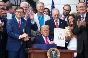 President Donald Trump shows his signature on the One Big Beautiful Bill Act, surrounded by Republican lawmakers.