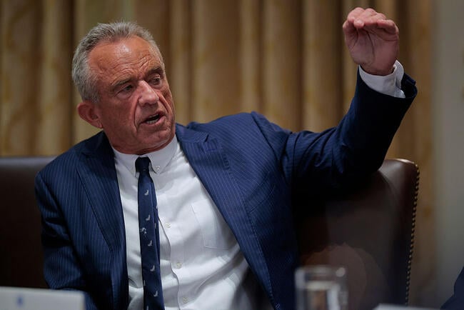 Health and Human Services Secretary Robert F. Kennedy Jr., a man with gray hair and extremely ruddy skin, wearing a blue suit and tie.