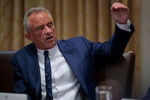 Health and Human Services Secretary Robert F. Kennedy Jr., a man with gray hair and extremely ruddy skin, wearing a blue suit and tie.