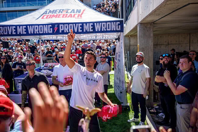 A photo of Charlie Kirk, founder of Turning Point USA, throwing T-shirts at the crowd upon arriving for a speaking event at Utah Valley University Wednesday; behind him is a tent that reads "The American Comeback/Prove Me Wrong." Kirk was shot and killed during the event.