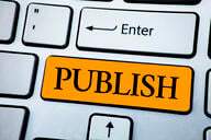 A computer keyboard with a big orange key that says "PUBLISH," directly beneath the enter key.