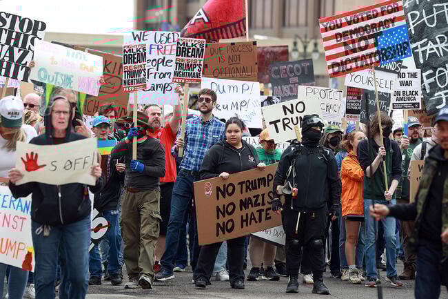 Protesters carry signs during a "Hands Off" protest rally in Detroit, Michigan.