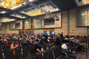 Hundreds of student affairs staff sit in a ballroom facing a stage
