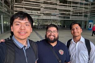 Two students smile for a selfie with an alumnus of Harvey Mudd College during a job-shadow experience