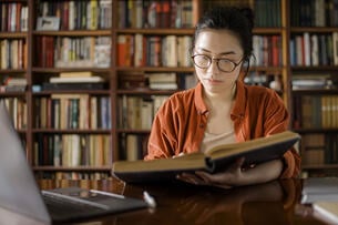 A woman researches a book in a library. 