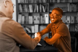 A student shakes hands with a job interviewer. 
