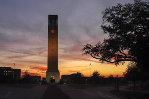The sun setting behind Texas A&M University’s clock tower.