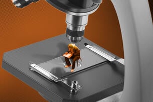 A miniature student sitting at a desk under a microscope.