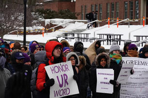 A photograph of a rally at the University of Rochester, with signs including "Agreement or Strike!"
