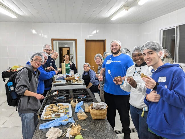 A group of young people work preparing meals wearing blue sweatshirts and hairnets