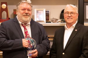 A photograph of Marshall Brain II, holding an award, standing next to North Carolina State University chancellor Randy Woodson.